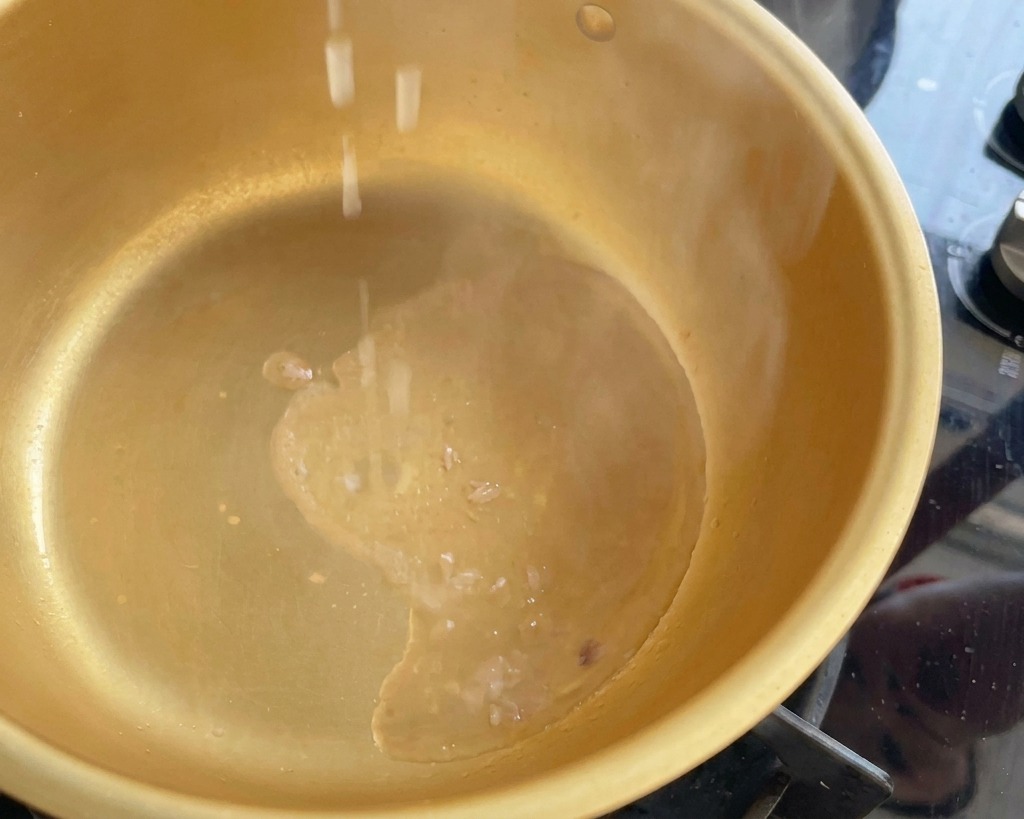 Gehackte Frühlingszwiebelstücke fallen in einen dampfenden goldenen Topf mit heißem Thunfischöl.