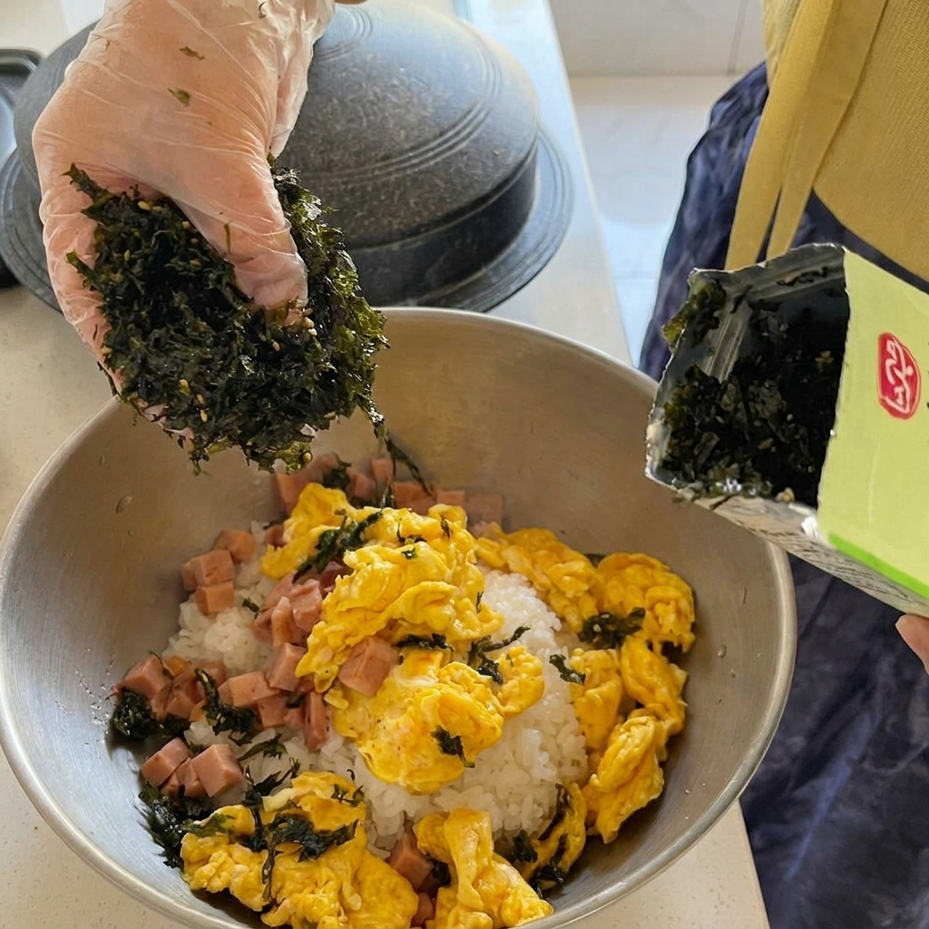 Große Stücke Dosen-Thunfisch werden in den köchelnden roten Kimchi-Eintopf in einem goldenen Topf gegeben.