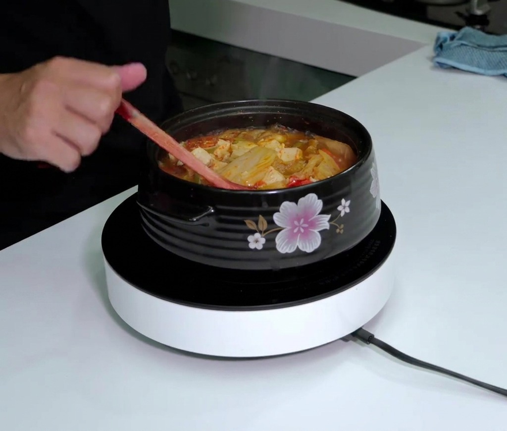 Tabasco wird in die kochende Kimchi-Suppe geträufelt.