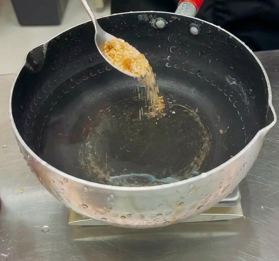 Würzpulver wird in einen Topf mit Wasser gegeben, um die Brühe für den Budae-jjigae vorzubereiten.