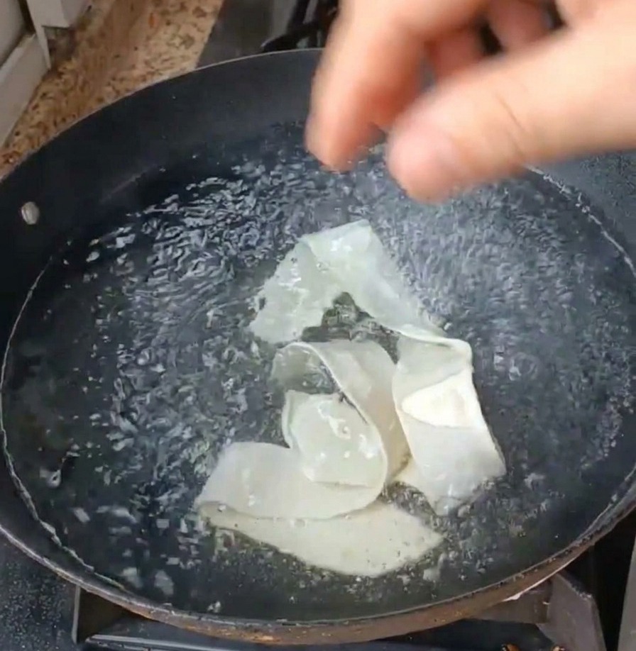 Breite Nudeln und grüner Salat werden in einen Topf mit sprudelnd kochendem Wasser gegeben.