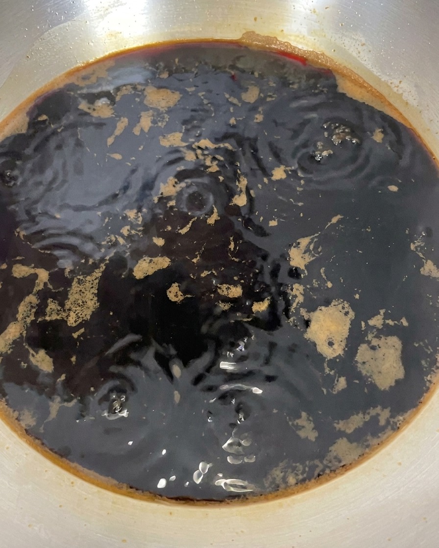 Die dunkle Sauce im Topf zeigt nach dem Ausschalten der Hitze nur noch kleine Bläschen.