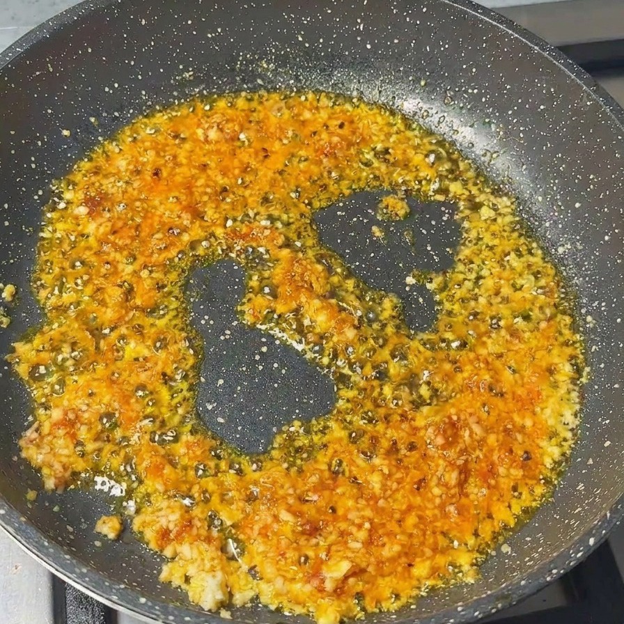 Schweinehackfleisch wird in die Pfanne mit Knoblauch und Garnelenpaste eingerührt.