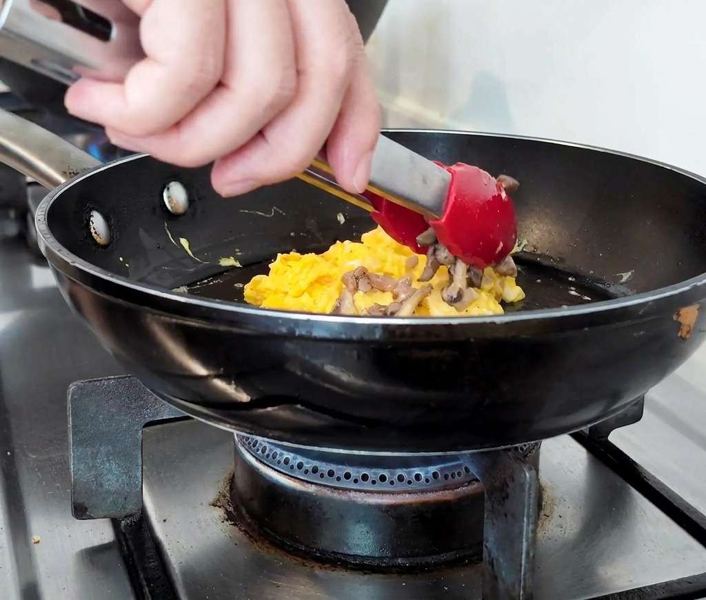 Die Hackfleisch-Pilz-Mischung wird auf das Rührei in der Pfanne gehäuft.