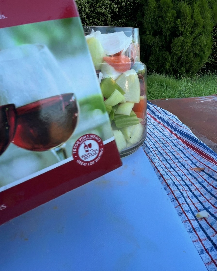 Rotwein wird aus einer Karaffe in ein Glas mit rohen Rinderrippen und Gemüse gegossen.