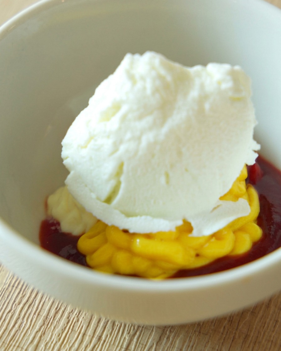 Eine weiße Keramikschüssel mit einer cremigen, orangefarbenen Burgersauce, die glatt gerührt wird.