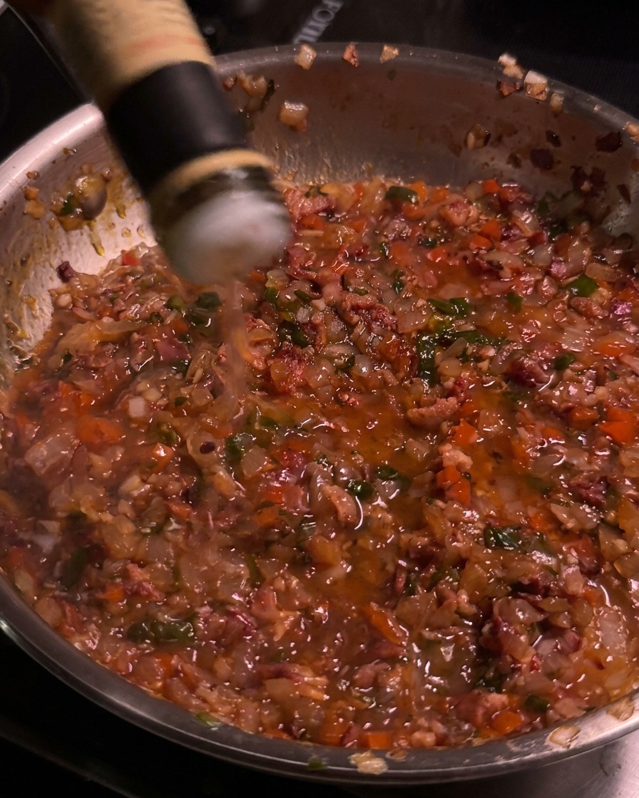 Apfelessig wird aus einer Flasche in die köchelnde Bacon-Jam-Pfanne gegossen.