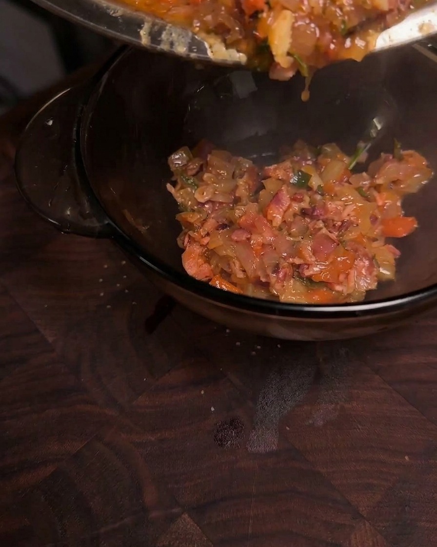 Dicke, glänzende, karamellisierte Bacon-Jam wird aus einer Pfanne in eine Klarglasschüssel gefüllt.