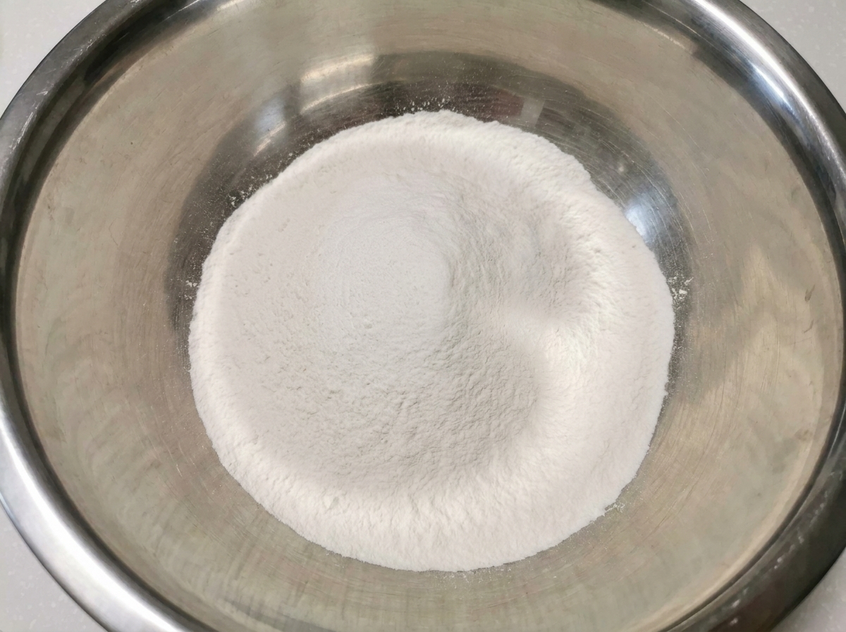 Ein sauberer, weißer Hügel aus Reismehl und Weizenmehl in einer großen Rührschüssel aus Edelstahl.
