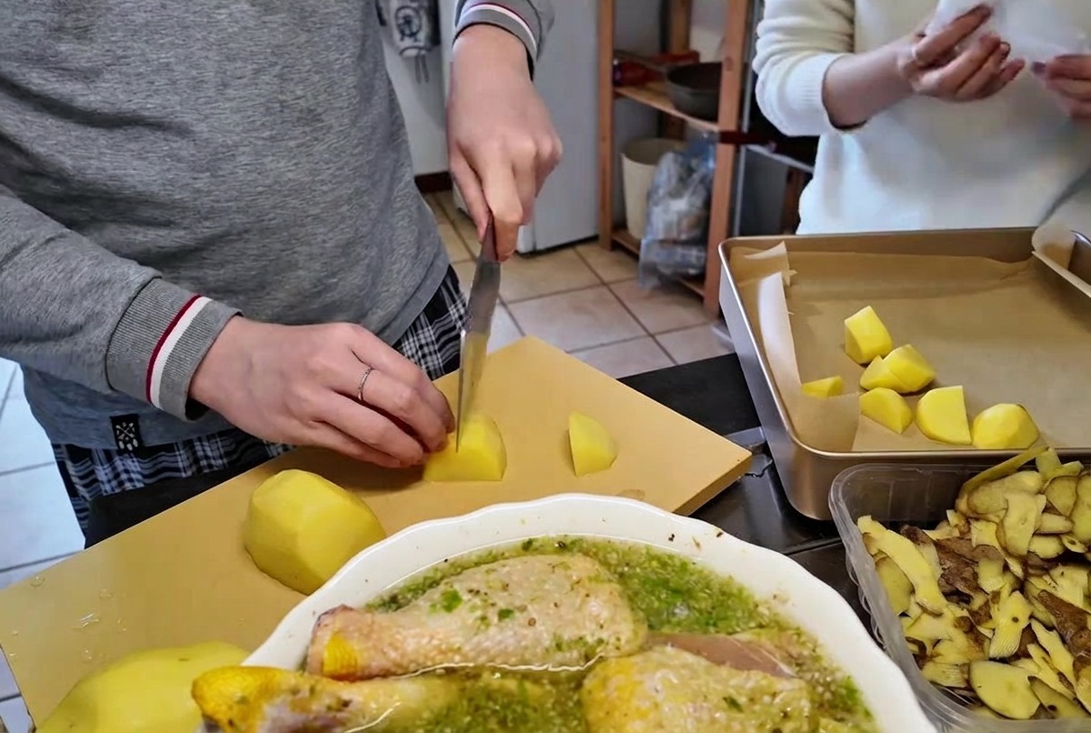 Schneiden von geschälten rohen Kartoffeln in mundgerechte Stücke auf einem Schneidebrett mit einem scharfen Küchenmesser.