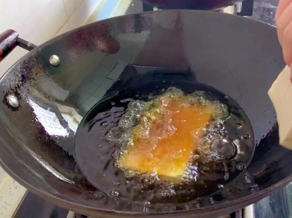 Feste Tofublöcke werden in einem Wok mit sprudelnd heißem Öl frittiert.