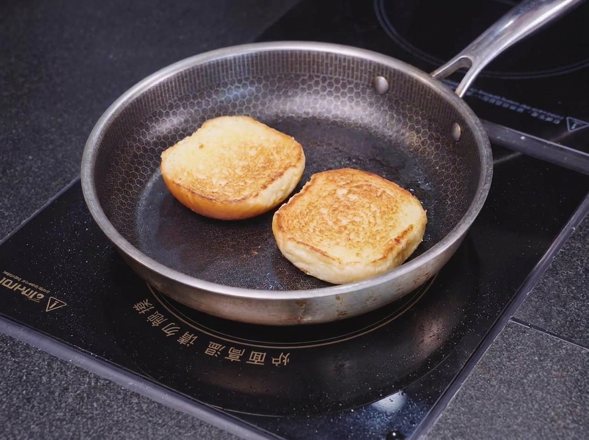 Zwei Hälften eines Brioche-Brötchens werden mit der Schnittseite nach unten in einer Pfanne mit Wabenmuster goldbraun und knusprig angebraten.