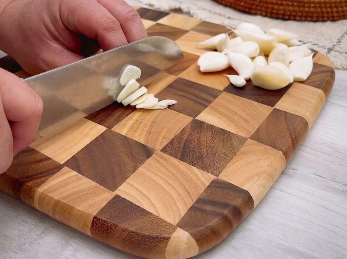 Fein gehackter Knoblauch verteilt auf einem Holzschneidebrett.