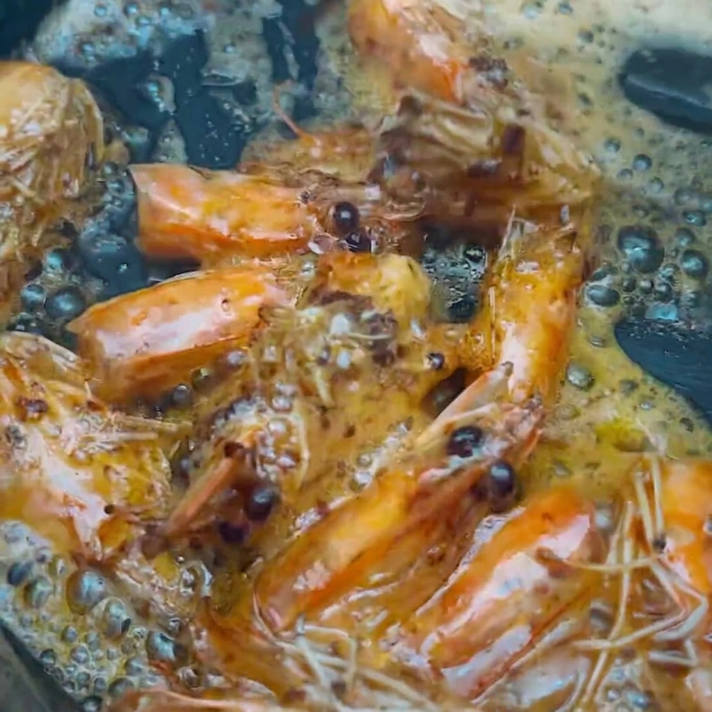 Garnelenköpfe werden mit Essstäbchen aus dem aromatisierten Öl gehoben.