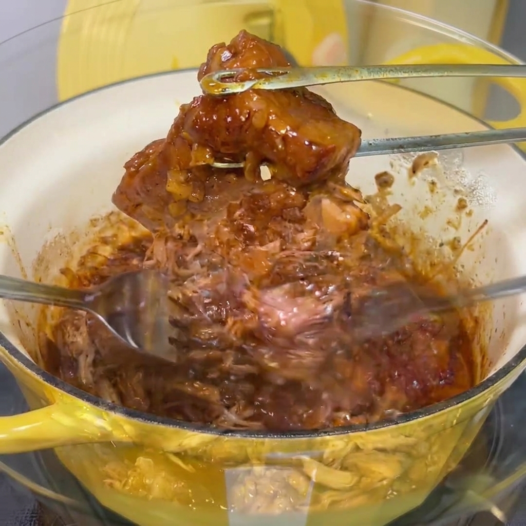 Das zarte Fleisch wird mit zwei Gabeln in einer Schüssel in feine Streifen gezupft.