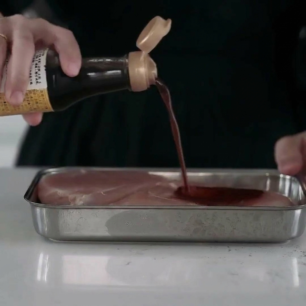 Saftige Hähnchenbruststücke in einer Metallschale, vollständig mit Marinade überzogen.