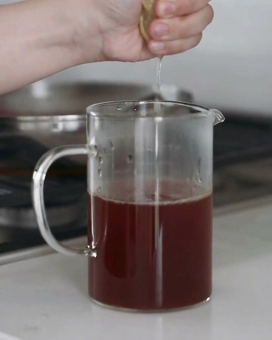 Frischer Zitronensaft wird in eine Schüssel mit Suppenbrühe gepresst.