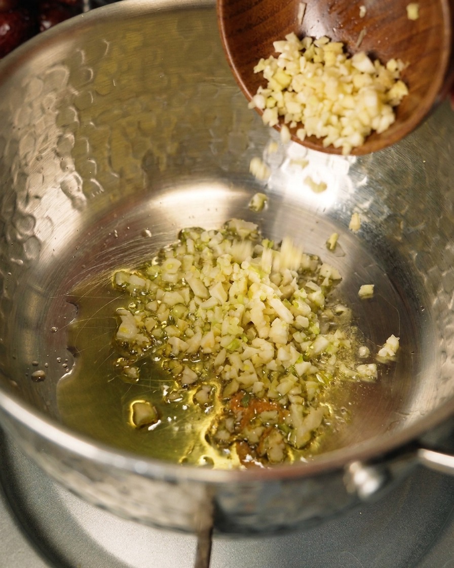 Zwiebeln und Knoblauch werden in einem Topf mit Olivenöl angebraten.