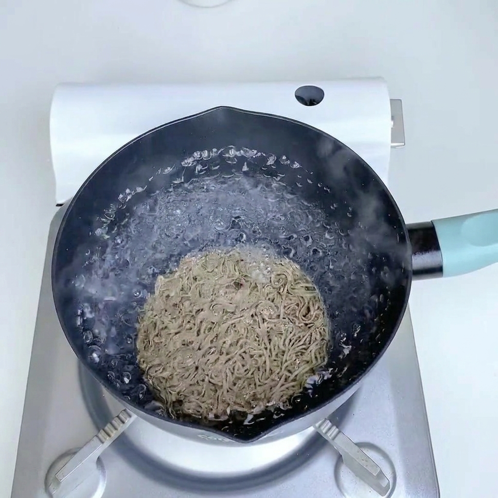 Buchweizennudeln kochen in einem Topf mit sprudelndem Wasser.