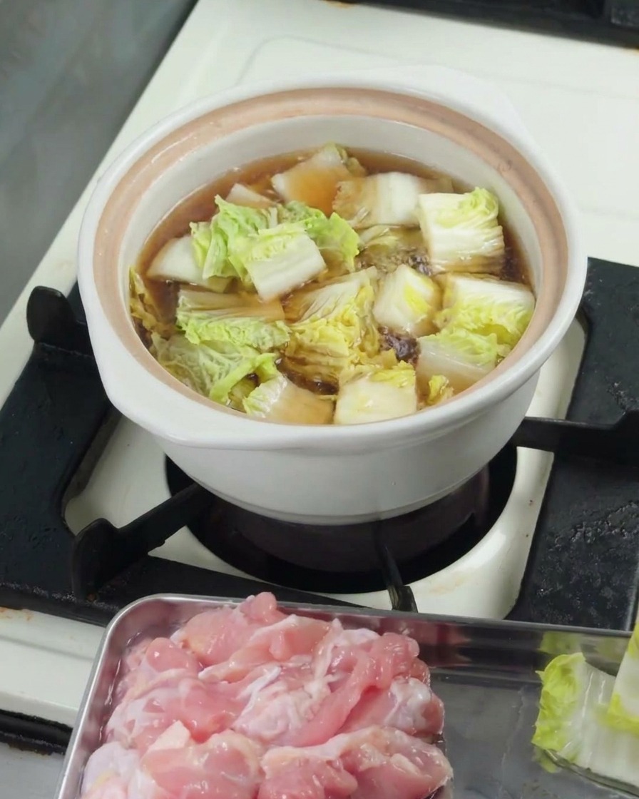 Gehackter Pak Choi simmert im Topf unter einem Deckel.