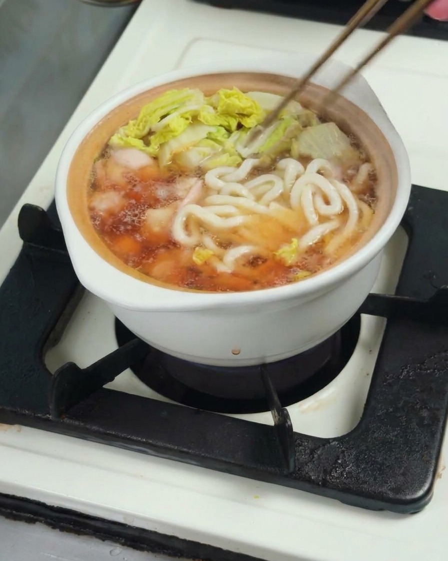 Udon-Nudeln werden in den Topf zur Suppe gegeben.