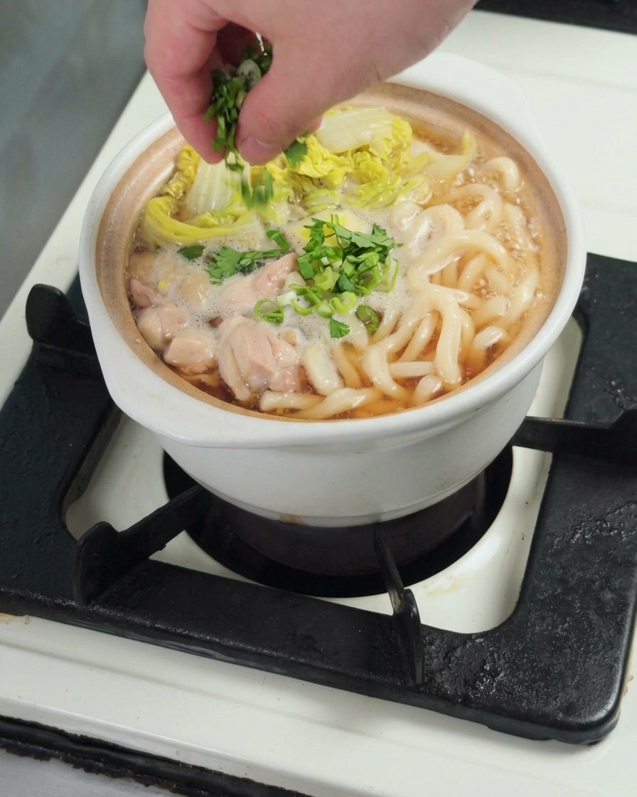 Frische Frühlingszwiebeln werden über die fertige Udon-Suppe gestreut.