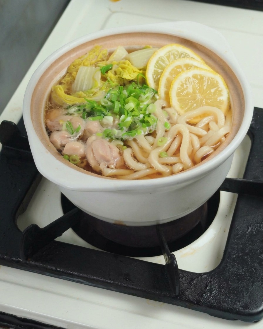 Zitronensaft wird in den Topf mit der fertigen Udon-Suppe gepresst.