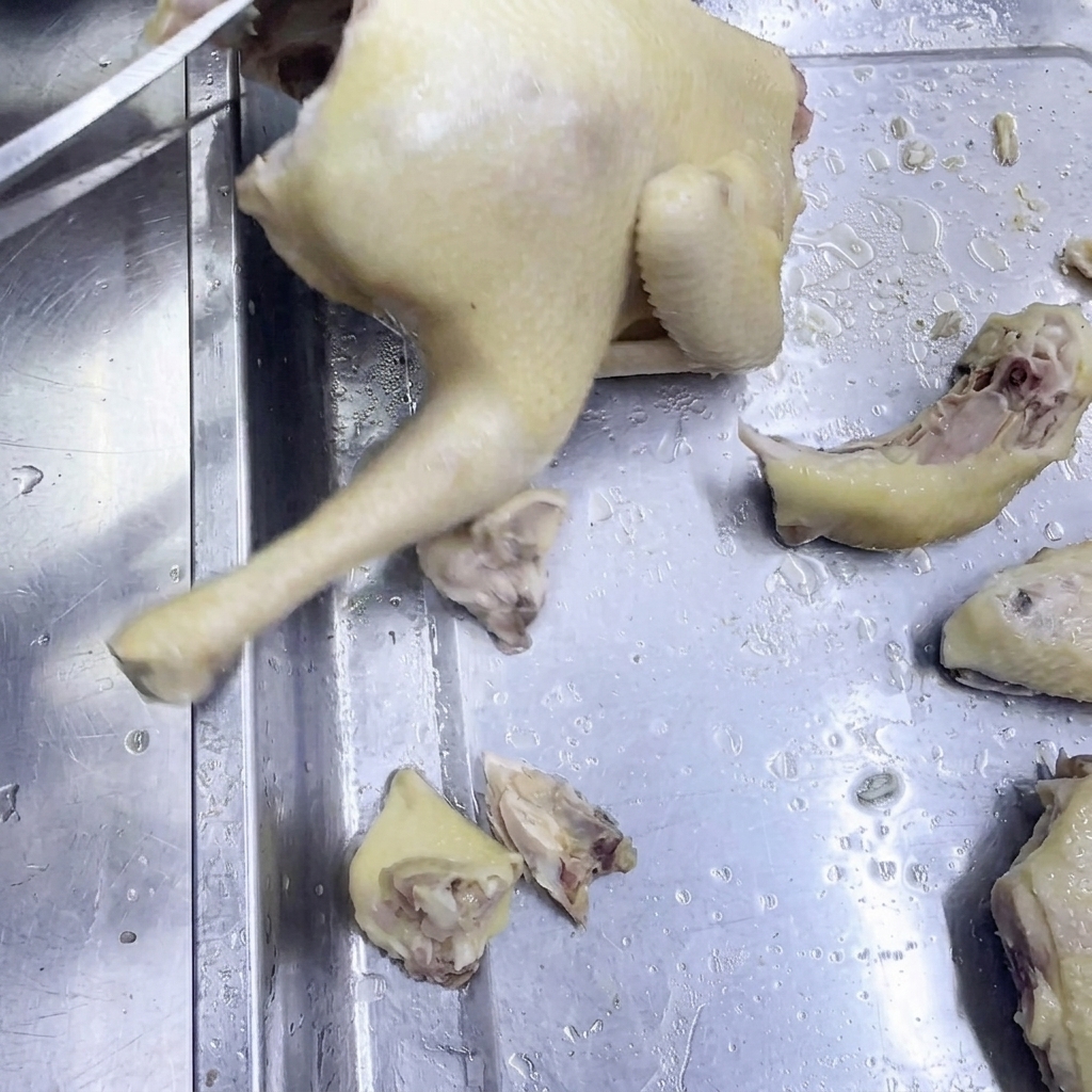 Ein Paar Küchenscheren schneidet gegartes Huhn auf einer Edelstahloberfläche.