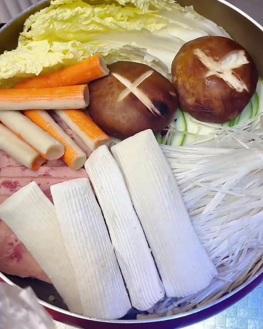 Fischfrikadellen und Surimi werden neben dem Fleisch und Gemüse in den Topf gegeben.