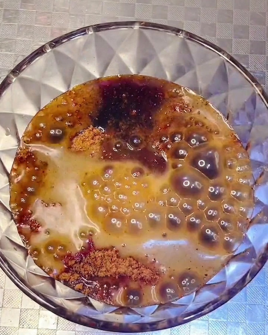 Eine dunkle, herzhafte Sauce wird über die Zutaten im Topf gegossen.