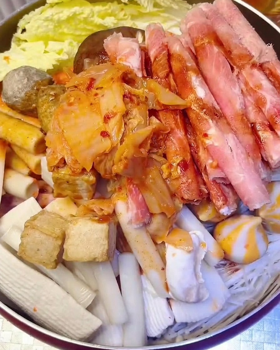 Gehacktes rotes Kimchi wird in den Topf gegeben, während Wasser hinzugefügt wird.