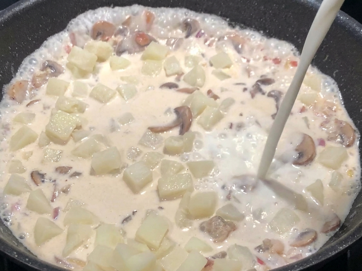 Milch wird hinzugefügt, während die Suppe simmert und sämig wird.