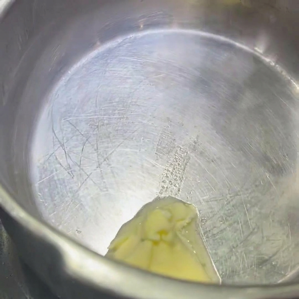 Ein Stück Butter schmilzt in einem Edelstahl-Topf.