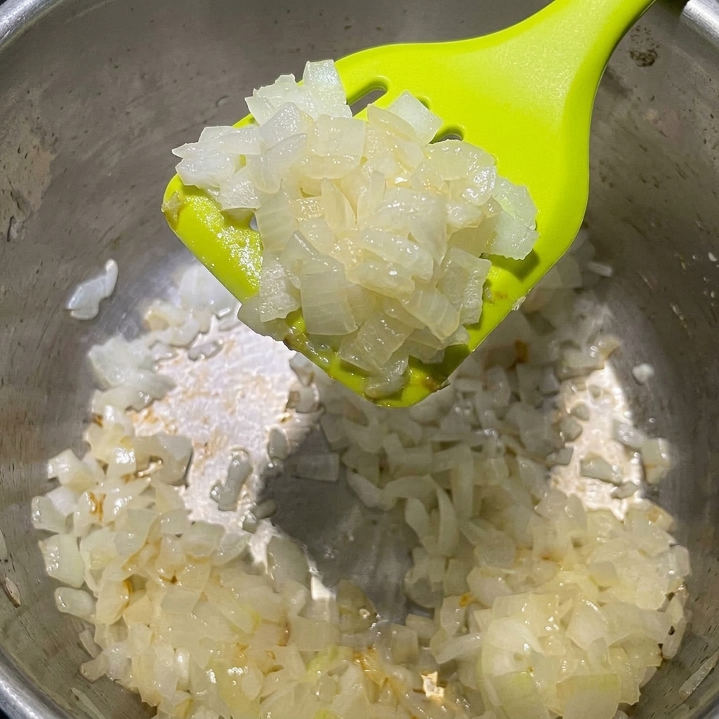 Gewürfelte weiße Zwiebeln in einem Topf mit geschmolzener Butter.