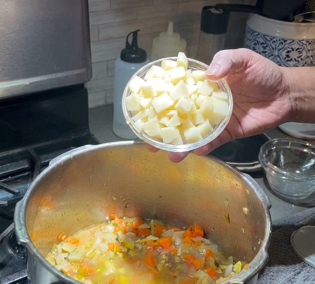 Kartoffelwürfel werden in die köchelnde Suppe gegeben.