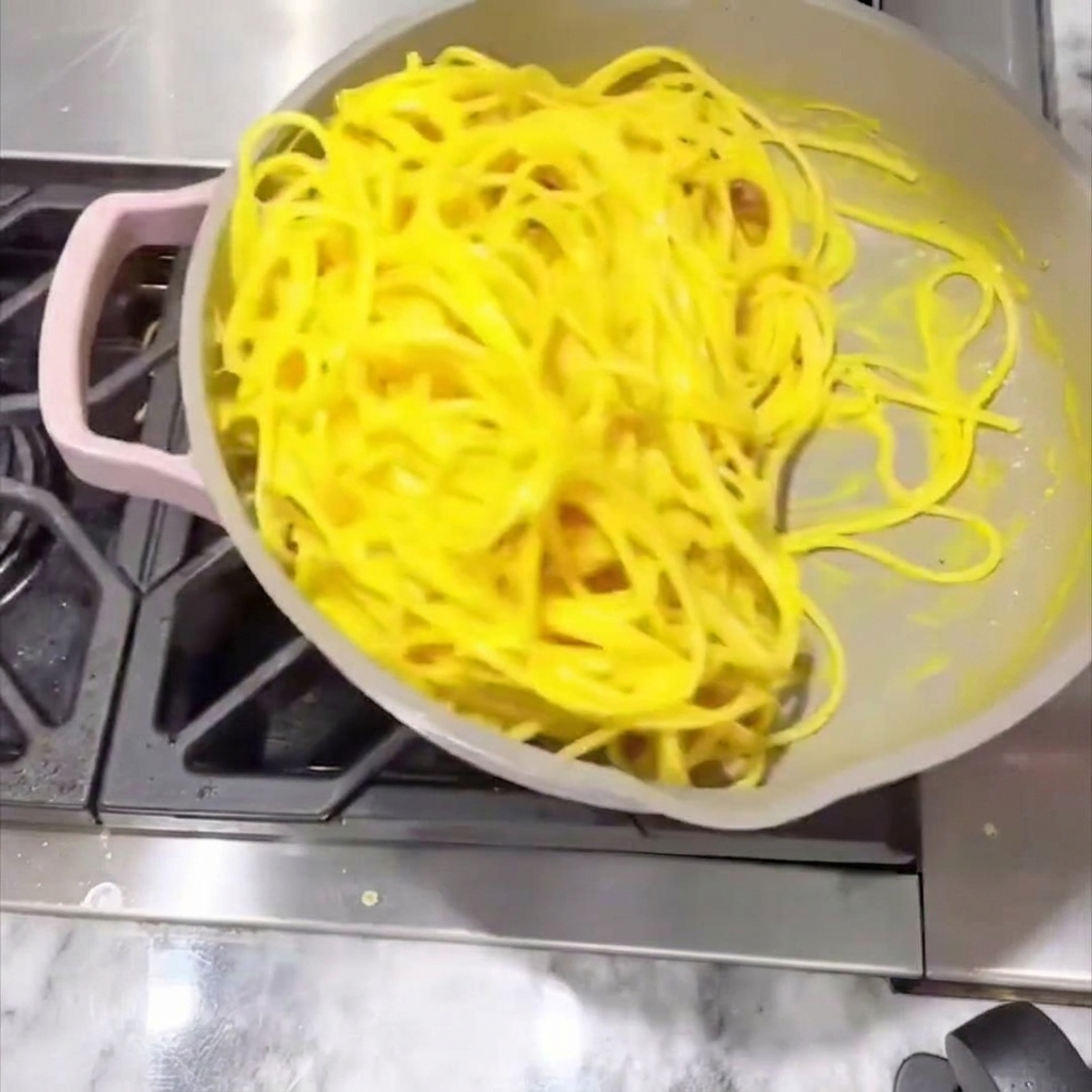 Spaghetti werden in der Pfanne gerührt, bis die Sauce cremig ist und alles gleichmäßig überzieht.