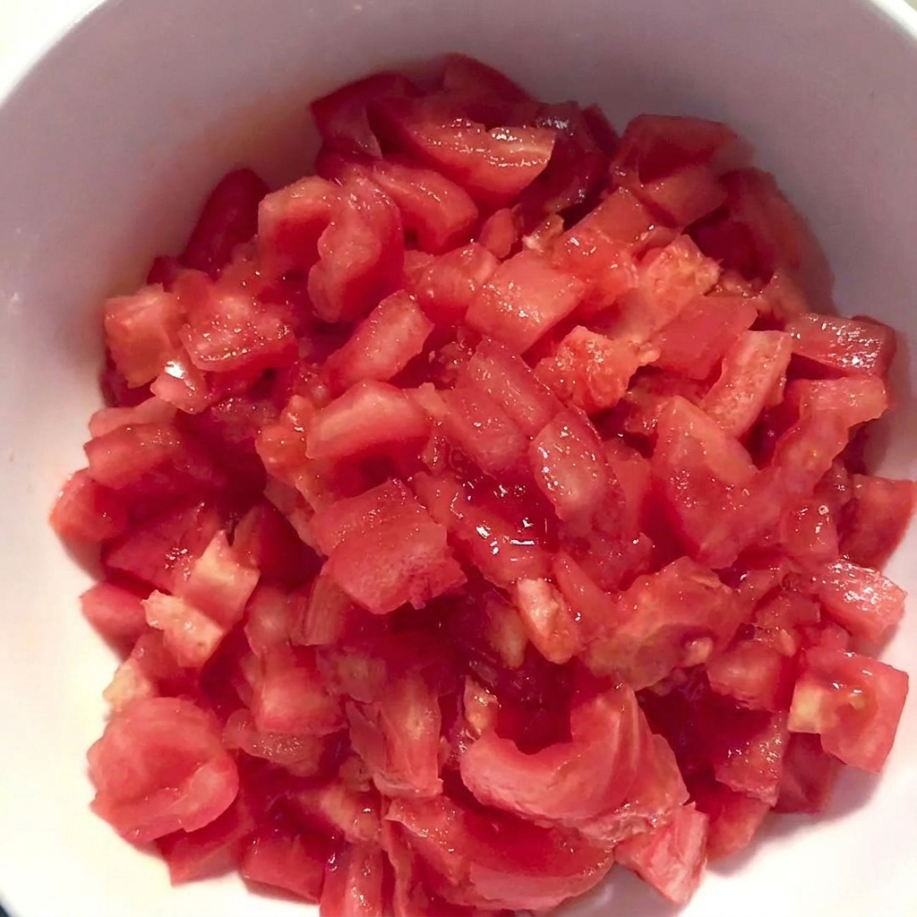 Eine weiße Schüssel gefüllt mit frisch gewürfelten, gehäuteten Tomaten.