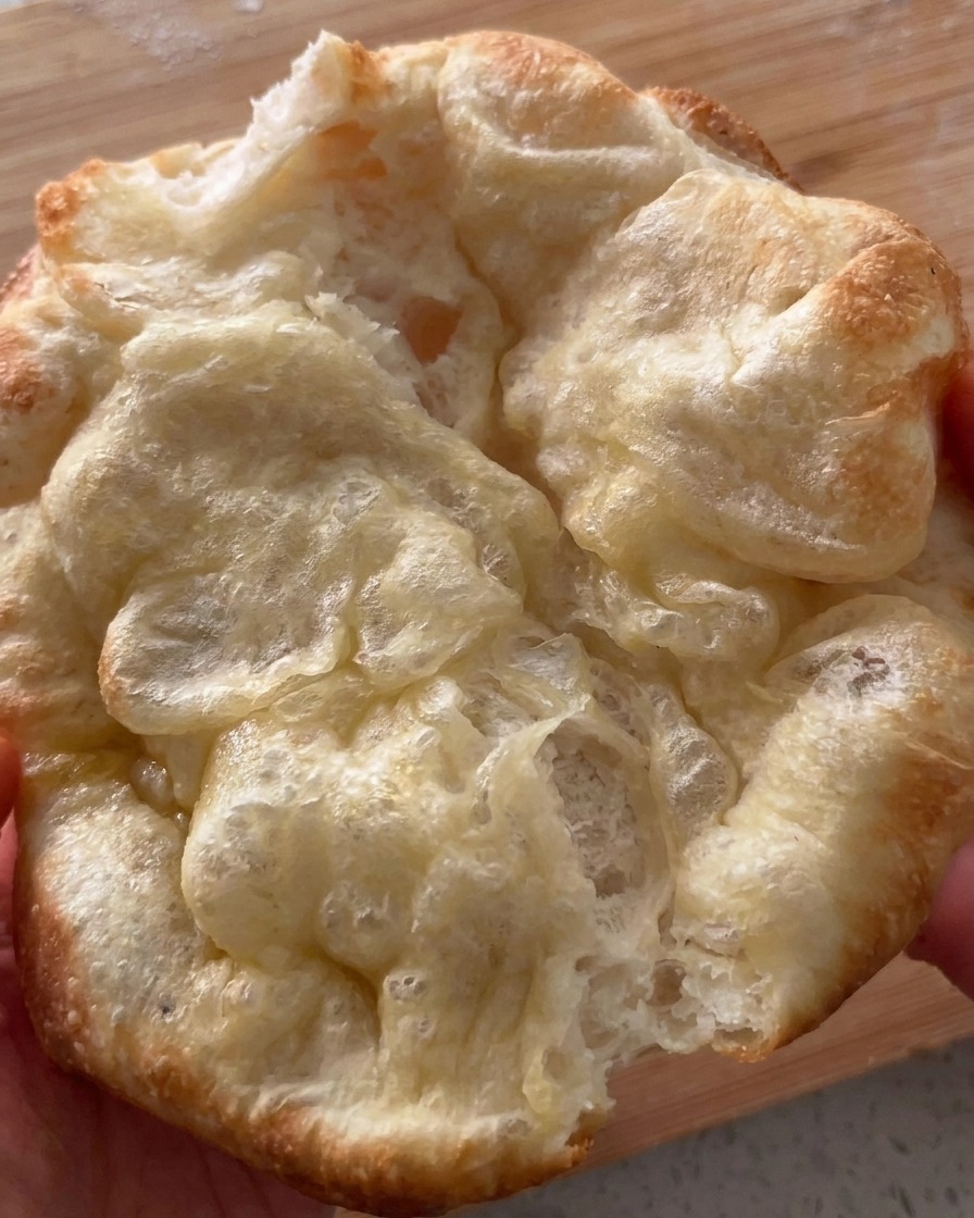 Ein frisch gebackenes, knuspriges Pizza-Brot wird vorsichtig aufgeklappt.
