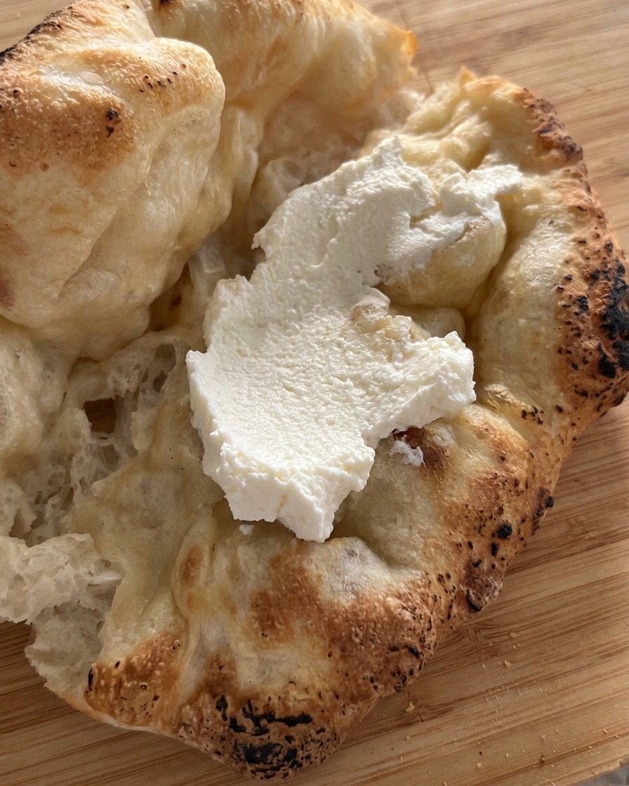 Eine großzügige Schicht Ricotta wird in das offene Pizza-Brot gestrichen.