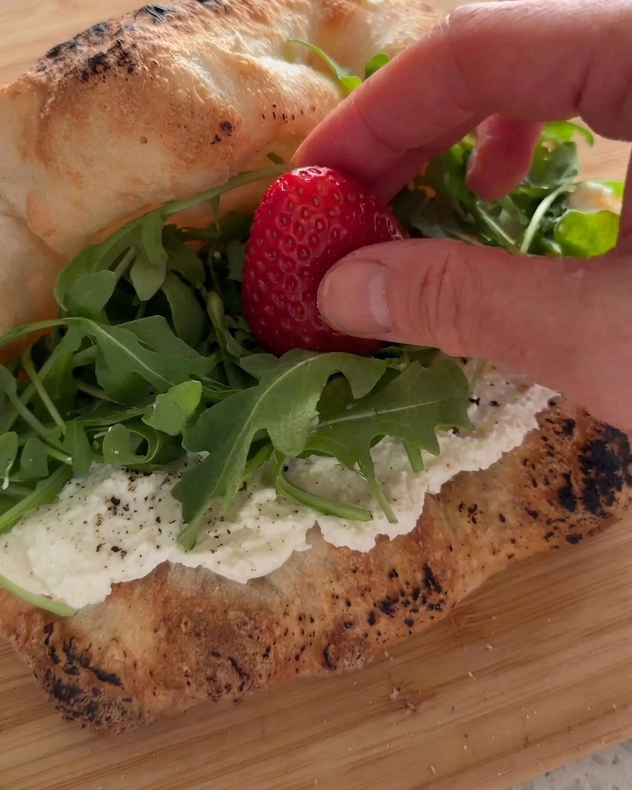 Frische Erdbeeren werden auf ein Rucola-Bett im Ricotta-Sandwich gelegt.