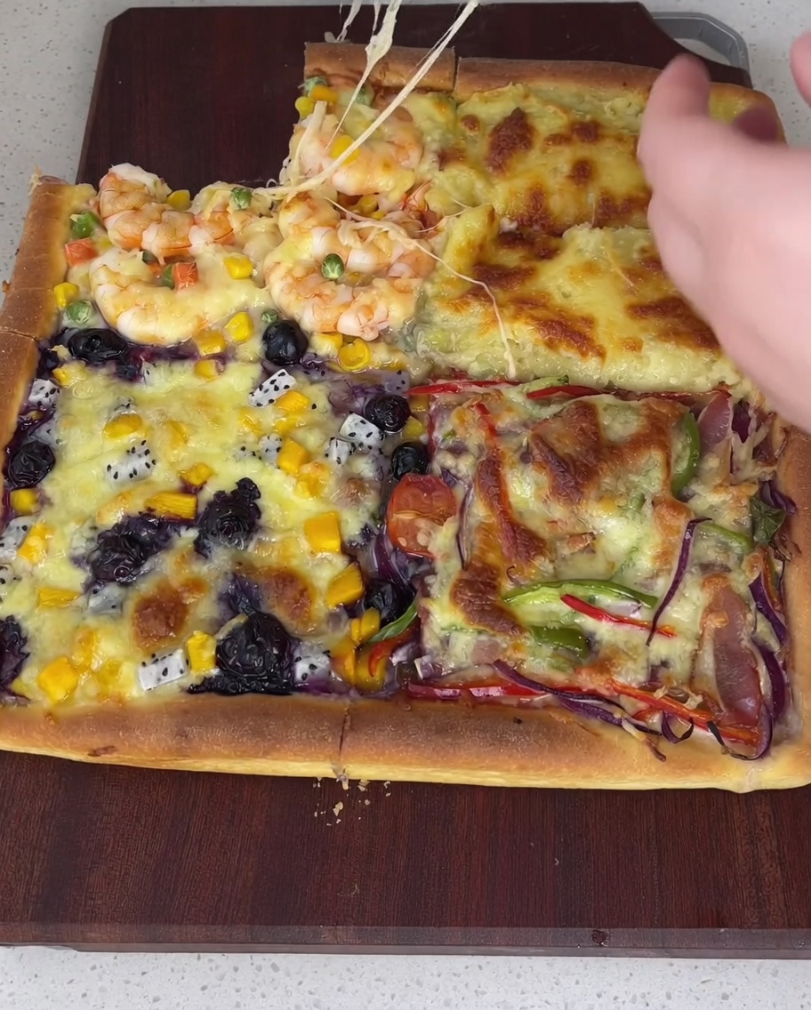Weißes Salatdressing wird auf zwei Viertel und rote Tomatensauce auf die restlichen zwei Viertel eines vorgebackenen, quadratischen Pizzabodens gestrichen.