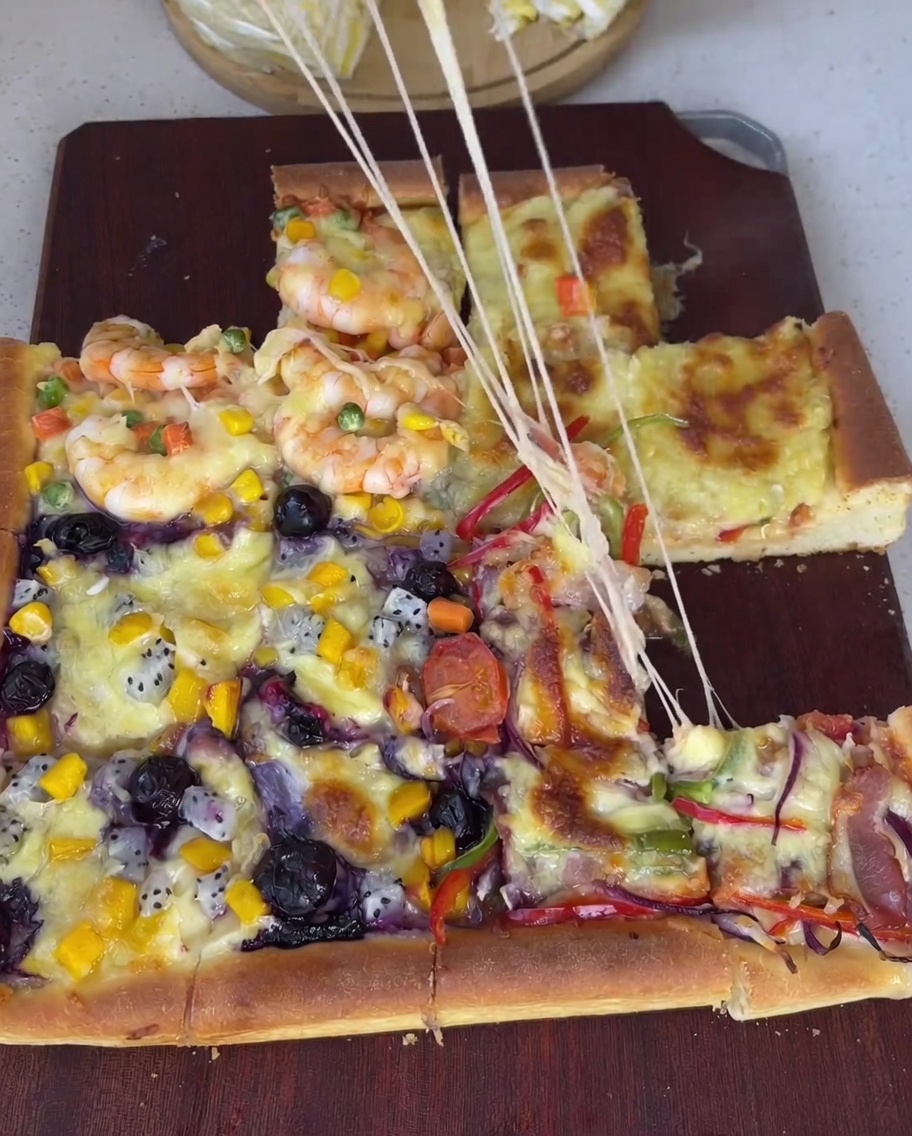 Rohe, geschälte Garnelen werden zusammen mit gemischten Erbsen, Mais und gewürfelten Karotten auf einem Teil der Pizza verteilt.
