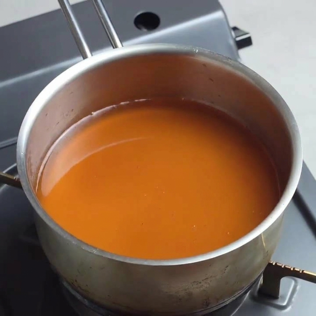 Ein Topf mit einer dunkel-bernsteinfarbenen Ramen-Basis köchelt bei mittlerer Hitze.