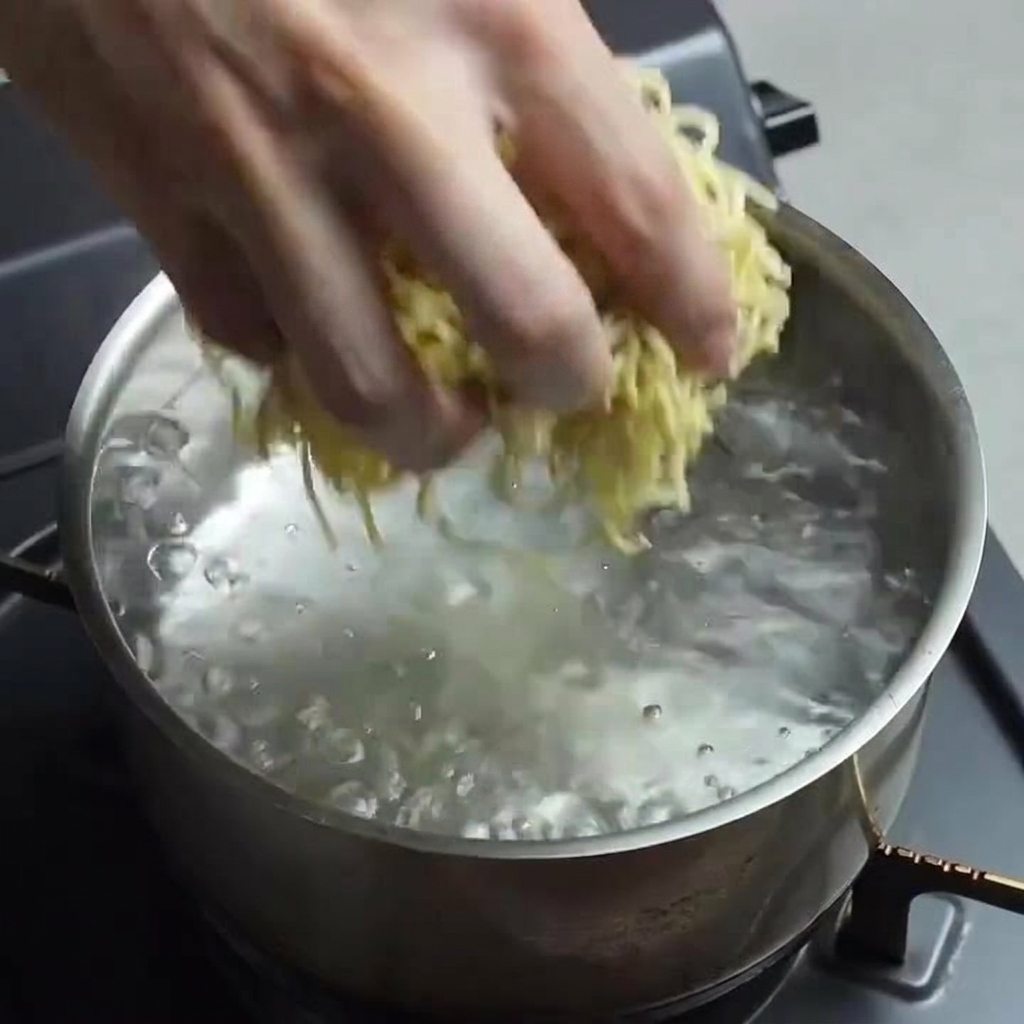 Eine Hand gibt vorsichtig frische Ramen-Nudeln in einen Topf mit sprudelnd kochendem Wasser.