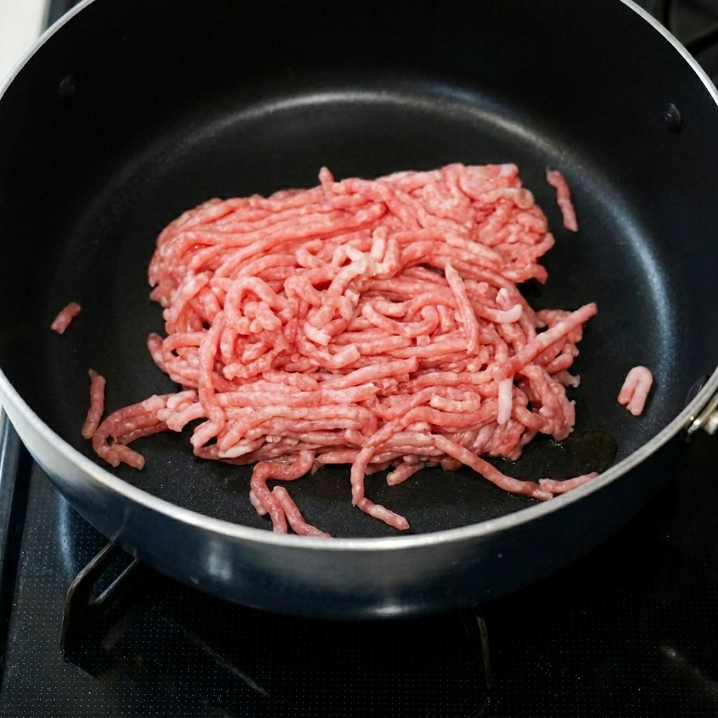 Schweinehackfleisch brutzelt in einer Pfanne zusammen mit scharfer Bohnenpaste und Knoblauch.