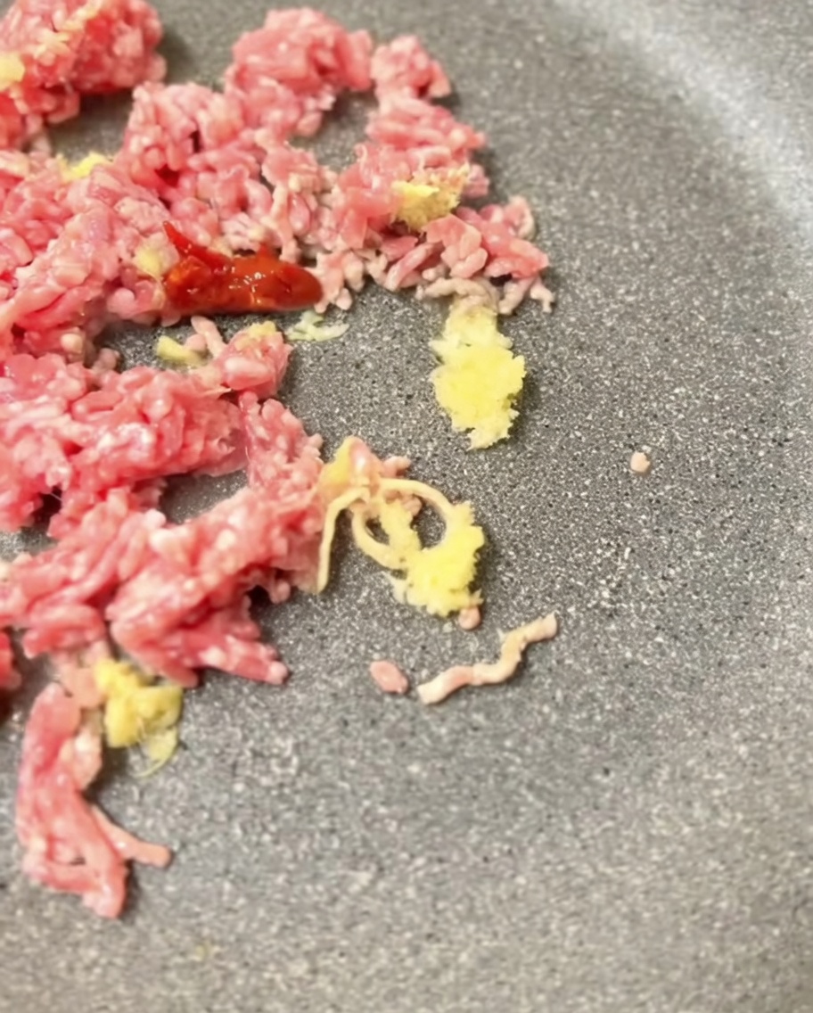 Misopaste wird unter das gebräunte Schweinefleisch in der Pfanne gemischt.
