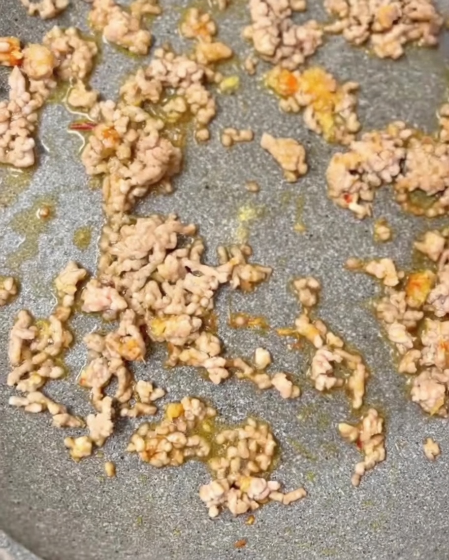 Gewürze, darunter gemahlener Sesam und Hühnerbrühepulver, werden in die Pfanne gegeben.