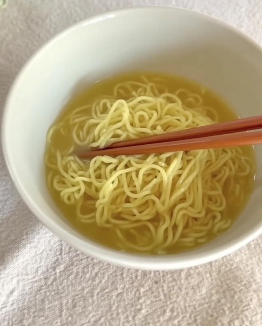 Cremige Tantanmen-Brühe wird über vorbereitete Nudeln in einer Schüssel gegossen.