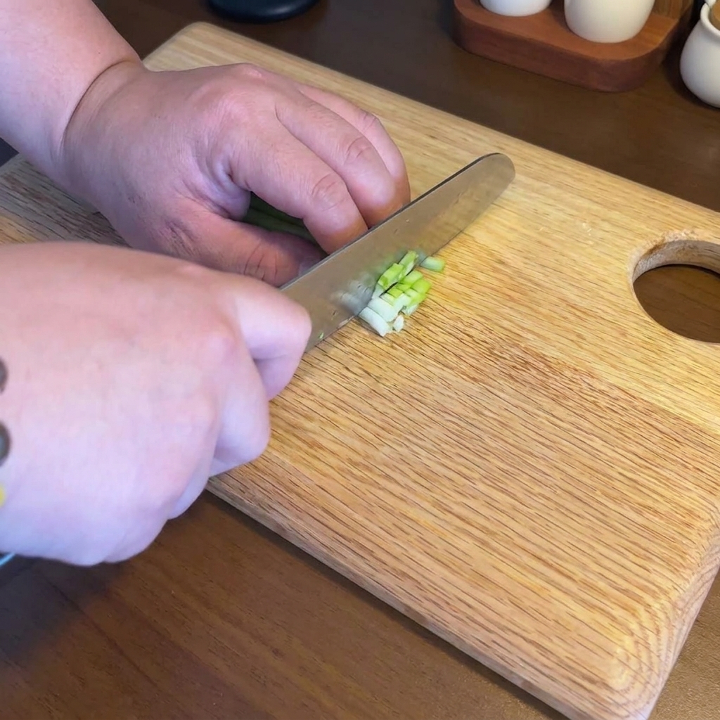 Fein gehackter Knoblauch, Ingwer und Frühlingszwiebeln auf einem Holzbrett.