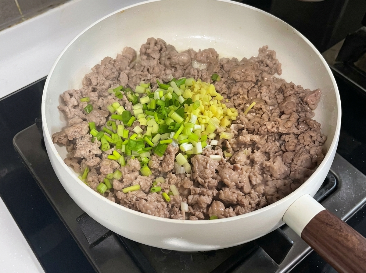 Schweinehack in der Pfanne vermischt mit gehackten Aromaten und Pasten.